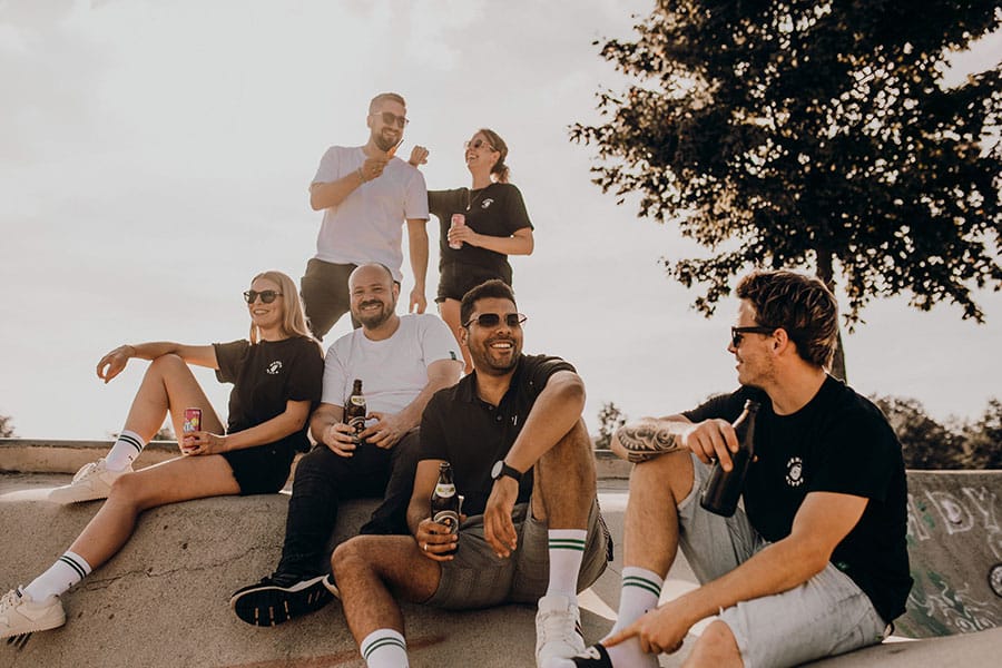various employees of Absaugwerk sit casually at the halfpipe and drink soda and beer