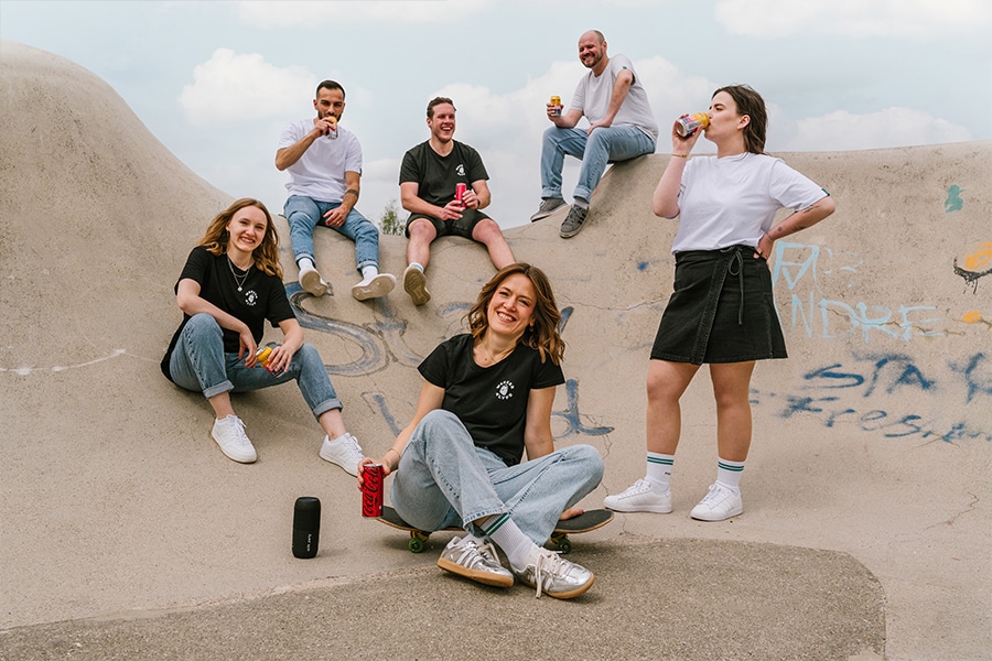 verschiedene Mitarbeiter von Absaugwerk sitzen lässig an Halfpipe und trinken Limo und Bier